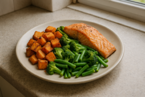 Bord met zalm, zoete aardappel en groene groenten in een lichte setting
