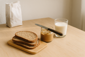 Eenvoudig ontbijt met volkorenbrood, notenpasta en een glas plantaardige drank op een lichte tafel