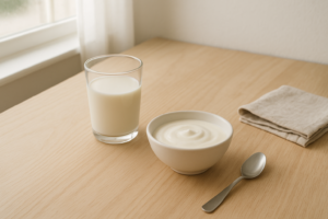 Eenvoudige flatlay met glas melk en schaaltje yoghurt op een lichte keukentafel