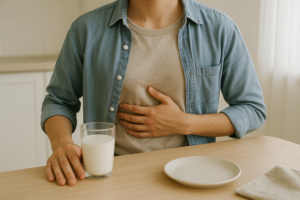 Persoon met lichte buikklachten aan de ontbijttafel naast een glas melk
